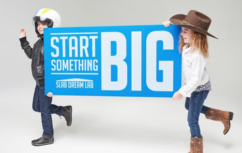 Boy in helmet and girl in cowboy hat hold Custom printed Baseplate: Start Something Big